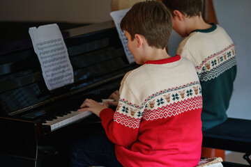 two preteen boys playing piano in living room. Children having fun with learning to play music...