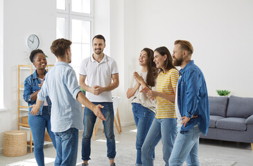 Obraz premium Joyful excited people listening interesting, exciting and funny story of their male friend. Man tells something to his multiracial young friends during meeting at home. Friendly conversation concept.