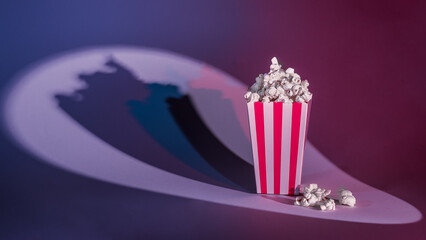 Popcorn bag in a spotlight with colored shadows. Concept cinema, hall and theater.