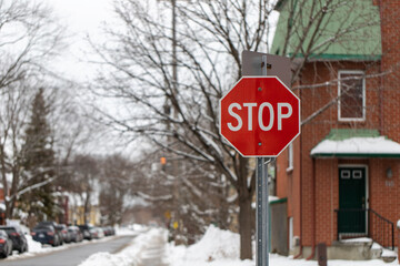 Stop sign in a residential neighborhood at crossroads in winter. Cars parking along the street.