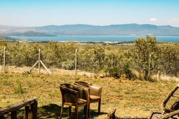 Chairs under the tree on a fire place in the wild against the background of Lake Naivasha in Rift Valley, Kenya