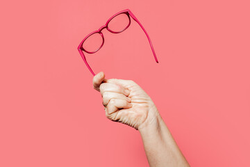 Crop person showing glasses on pink background