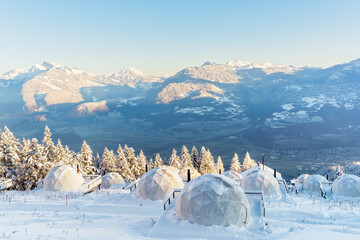 Whitepod winter igloo hotel in swiss mountauns covered by white snow at sunrise at morning with amazing view. Luxury pods in eco hotel. - obrazy, fototapety, plakaty