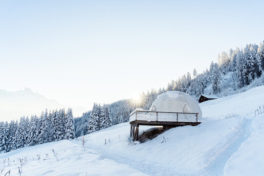 Whitepod winter igloo hotel in swiss mountauns covered by white snow at sunrise at morning. Luxury pods in eco hotel.