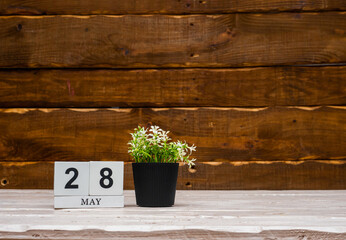 May calendar with number  28. Planner copy space on a wooden brown background. March number icon. Place for text background calendar