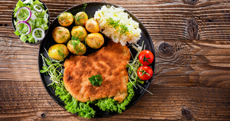 Pork cutlet coated with breadcrumbs with potatoes and cabbage