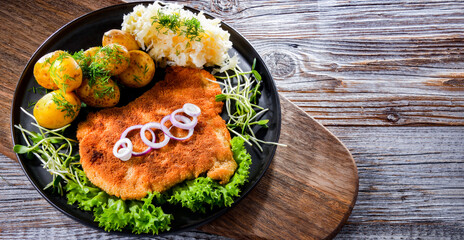 Pork cutlet coated with breadcrumbs with potatoes and cabbage