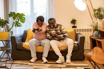 senior couple play console game on sofa