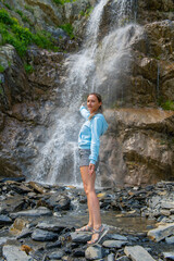 one girl in naked clothes stands at the waterfall