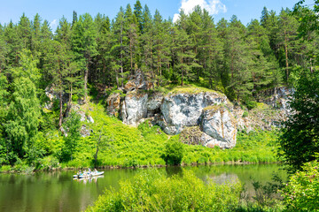 Fototapeta na wymiar Rafting on the Chusovaya river against the background of rocks and coniferous trees and greenery on a sunny summer day, Ural, Sverdlovsk region, Russia