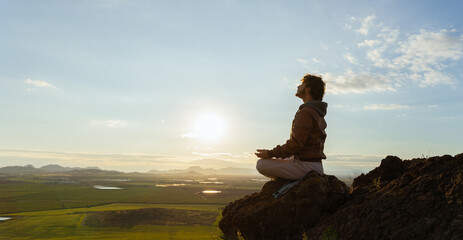 Man sitting on top of a mountain in a meditative pose taking breaths. Spiritual meditation retreat