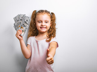 Small professor fun humor kid girl holding dollar money in the hand and showing thumb up sign on blue background. - 566362045