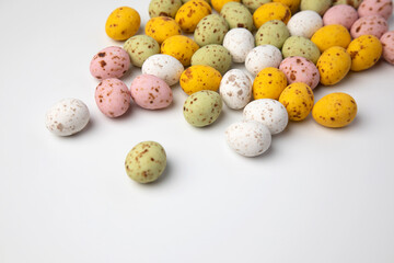 Multi-colored chocolate decorative eggs on a white background. Happy Easter background. Flat lay