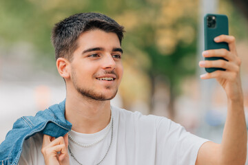 young man on the street with phone making selfie or photo