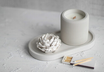 Candle, white color, in a unique candle holder concrete and oval coaster made from concrete in white colors.