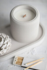 Candle, white color, in a unique candle holder concrete and oval coaster made from concrete in white colors. Matches for candles.