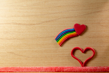 
Plastilina en forma de arcoíris (PRIDE) Y corazón en fondo de madera, concepto del día mundial...