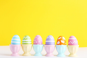 Row colorful easter eggs in stands on yellow background