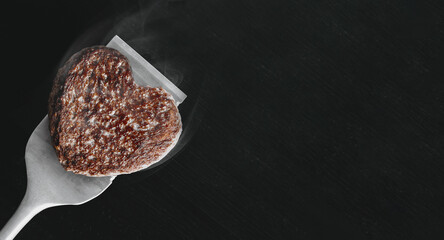 heart shaped beef burger patty on a grilled spatula. dark background place for text. valentines day celebration concept - 566371881