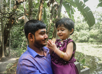 South asian young uncle holding his niece in arm in outdoor 