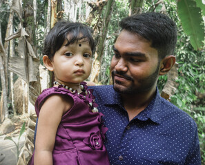 South asian young uncle holding his niece in arm in outdoor 