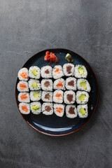 Set of different types of sushi rolls with salmon, tuna and avocado on a rustic background.Vertical view
