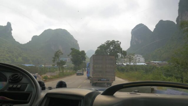 A bus drives towards the sugar loafs on the road damaged with trucks, in Yangshuo, China