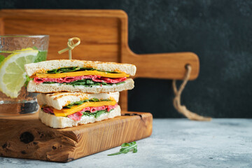 Two homemade sandwiches with sausage, cheese and arugula on a light concrete background