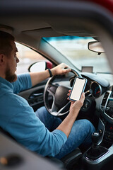 Man driver using mobile phone screen blank mockup on the road while driving a car