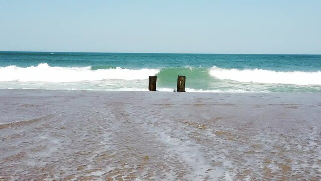Waves Crashing Against a Old Torn Down Dock On The Sand