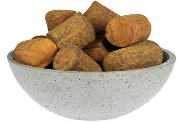 Dutch cinnamon candy sticks in a concrete bowl isolated on white background