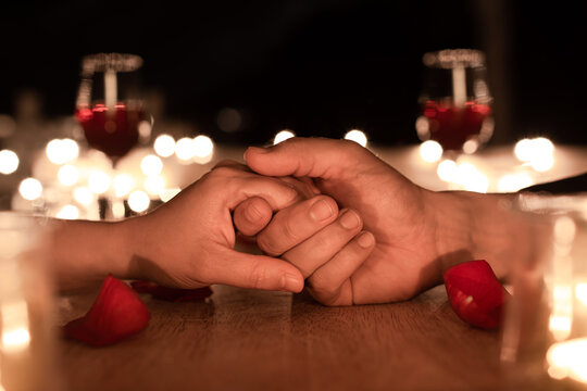 closeup of man and woman holding hands at candle light dinner. People in love, Valentine's Day concept 