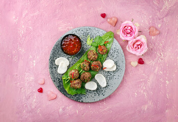 Traditional Valentine’s Day Asian street food meatballs served with krupuk prawn cracker and spicy chili sweet sour sauce on a Nordic design plate as top view with text space