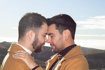 portrait of gay couple outdoors putting their heads together in a romantic way