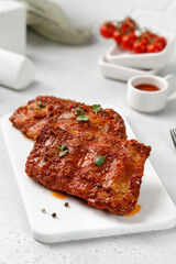 Cooked Marinated pork bbq ribs on ceramic white cutting board and white  background.