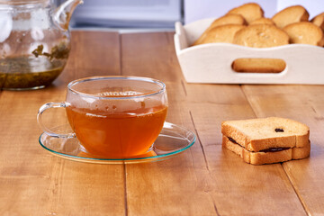 Tea in a glass cup on the wooden table and toast with plum jam.