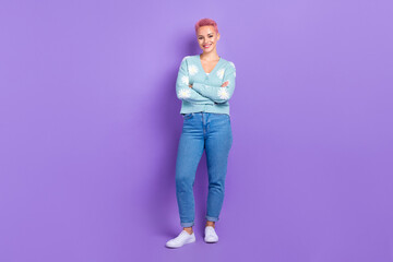 Full length photo of positive satisfied lady pink dyed hairdo crossed hands wear stylish blue cardigan nice jeans isolated on violet color background