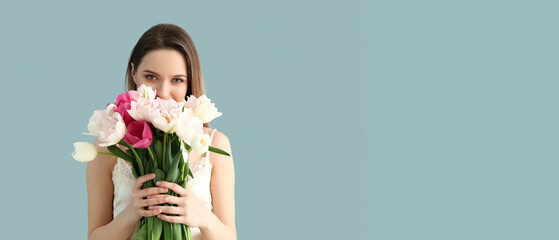 Pretty young woman with bouquet of beautiful tulips on light blue background with space for text