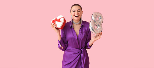 Stylish happy woman with gift and balloon in shape of figure 8 on pink background. International Women's Day