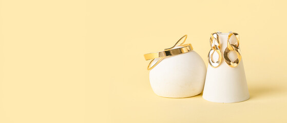 Modern podium with stylish golden jewelry on yellow background with space for text