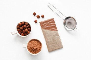 Milk chocolate with hazelnuts. Bowl with coco and nuts. White background
