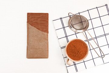 Chocolate bar, nuts, cocoa, strainer on white background