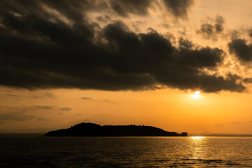 Fototapeta premium Lake at sunset with sun coming down off clouds and reflecting on water
