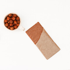 A bar of chocolate and bowl with cocoa on a white table