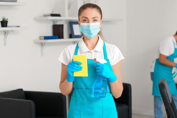Fototapeta na wymiar Female janitor with medical mask, rag and detergent in office