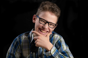 Child with glasses and curls laughing into camera against dark background