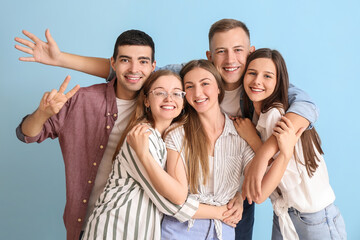 Group of happy friends hugging on blue background