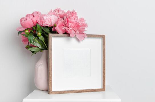 Square blank picture frame mockup with fresh peony flowers bouquet