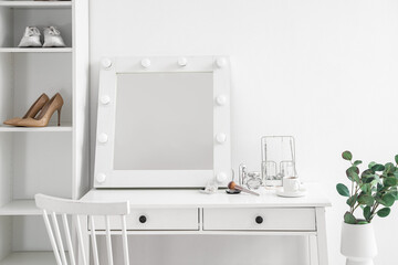 Table with mirror, cosmetics and jewelry in light makeup room