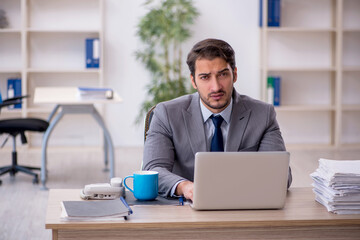 Young male employee and too much work in the office